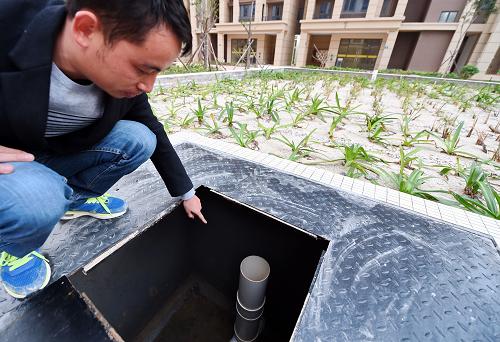 工作人員在翔安區(qū)洋唐保障性安居工程介紹雨水花園的地下儲(chǔ)水井（12月16日攝）。