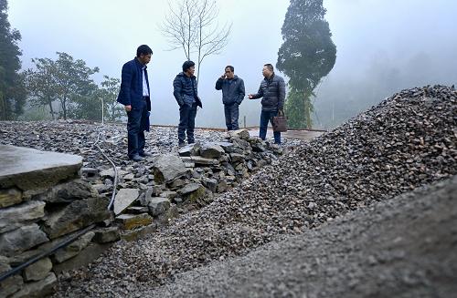 12月22日，湖北省宣恩縣縣辦公室“扶貧家長”譚發(fā)軍（右一）在椒園鎮(zhèn)石馬村貧困農(nóng)民曾召毅（左二）的房屋整修現(xiàn)場了解施工進(jìn)度。新華社發(fā)（宋文 攝）