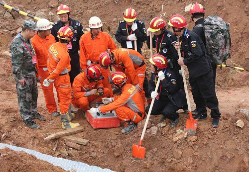 12月23日，天狼救援隊（黑衣）和武警官兵一起使用生命測試儀。在深圳滑坡災(zāi)害發(fā)生后，除了解放軍和武警部隊的救援力量，災(zāi)害現(xiàn)場還活躍著多支志愿者專業(yè)救援隊伍。他們與解放軍和武警部隊相配合，用專業(yè)的技術(shù)手段和技術(shù)能力開展救援。新華社記者 殷剛 攝