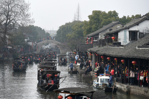 2月12日，游客乘坐游船在浙江西塘古鎮(zhèn)穿行。當日是大年初五，位于浙江省嘉善縣境內(nèi)的西塘古鎮(zhèn)持續(xù)迎來大批游客。在春節(jié)期間，西塘景區(qū)每日舉辦祭灶神、水上婚禮等特色民俗活動，讓游客感受到濃濃的傳統(tǒng)年味。新華社記者 黃宗治 攝