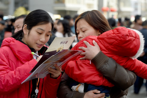 2月18日，在合肥市濱湖新區(qū)春風(fēng)行動(dòng)第十二屆濱湖新區(qū)大型招聘會(huì)現(xiàn)場(chǎng)，回遷居民孫永華（右）抱著自己3歲大的孩子前來(lái)登記應(yīng)聘信息，她想找一個(gè)小時(shí)工的工作。新華社記者 郭晨 攝